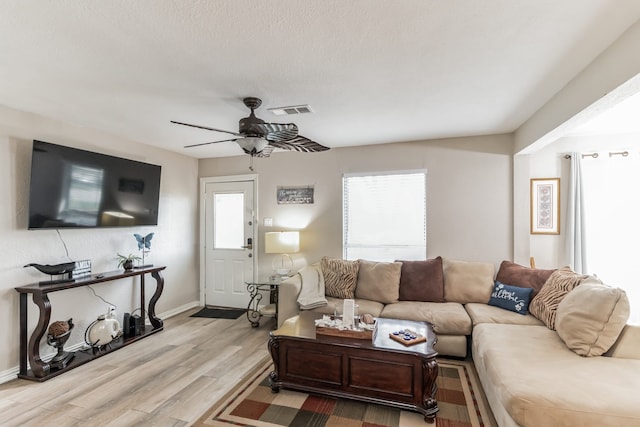 living room with ceiling fan, light hardwood / wood-style floors, a textured ceiling, and a wealth of natural light