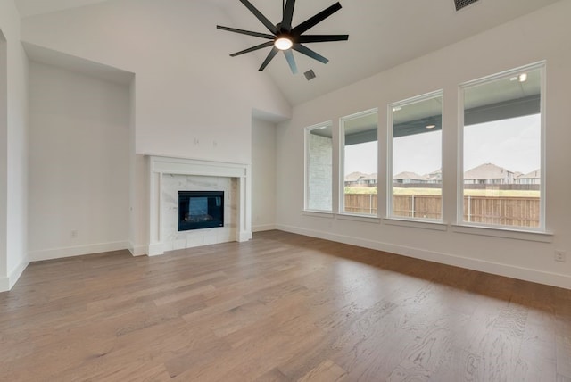 unfurnished living room featuring a fireplace, high vaulted ceiling, light hardwood / wood-style flooring, and ceiling fan