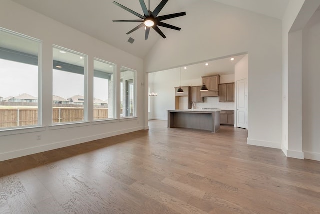 unfurnished living room with ceiling fan, high vaulted ceiling, and light wood-type flooring