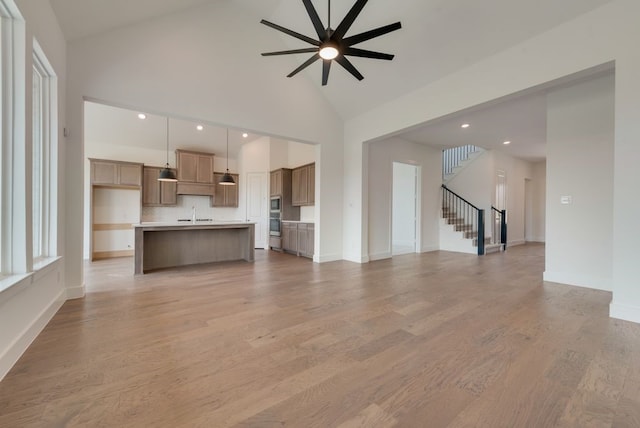 unfurnished living room featuring light hardwood / wood-style floors, high vaulted ceiling, and ceiling fan