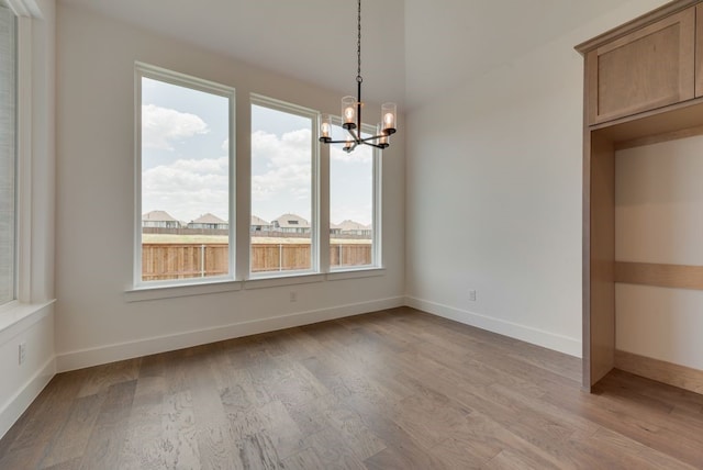 unfurnished dining area featuring light wood-type flooring and an inviting chandelier