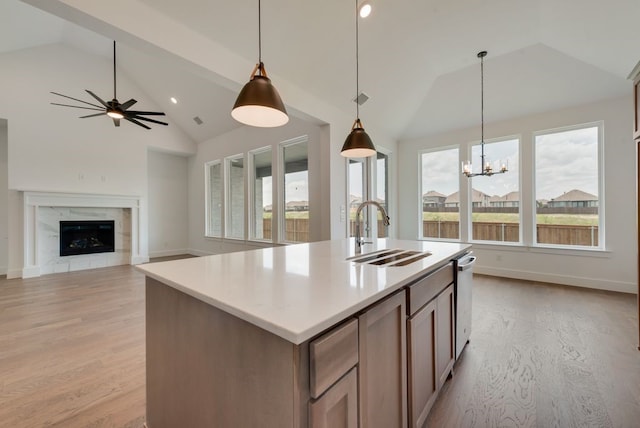 kitchen featuring a center island with sink, pendant lighting, a premium fireplace, and sink