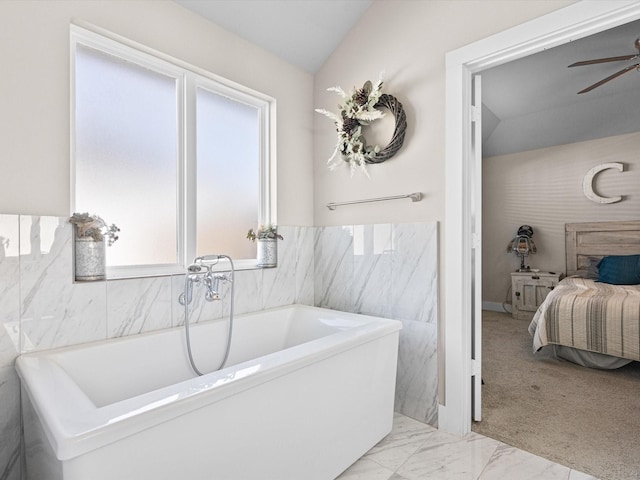 bathroom featuring ceiling fan, a washtub, and vaulted ceiling