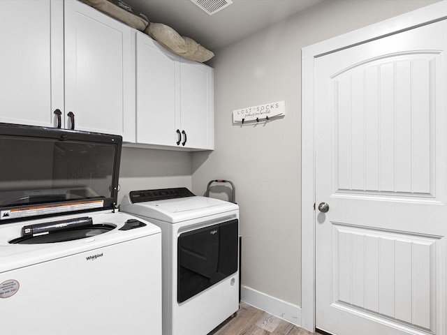 laundry room featuring light hardwood / wood-style flooring, washer and clothes dryer, and cabinets