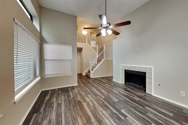 unfurnished living room featuring high vaulted ceiling, ceiling fan, dark wood-type flooring, and a tile fireplace