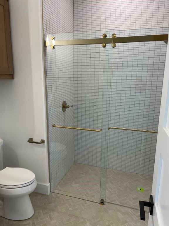 bathroom with toilet and a shower with shower door