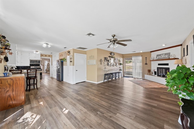 living room featuring hardwood / wood-style flooring, a brick fireplace, and ceiling fan