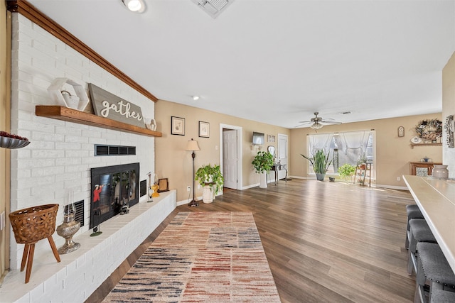 living room with a fireplace, wood-type flooring, and ceiling fan