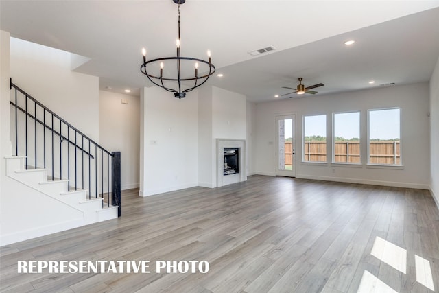 unfurnished living room featuring light hardwood / wood-style flooring and ceiling fan with notable chandelier