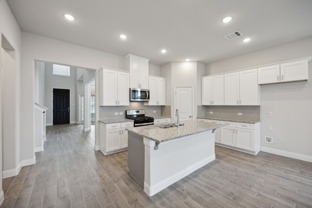 kitchen featuring appliances with stainless steel finishes, an island with sink, white cabinetry, and sink