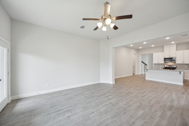 unfurnished living room with light wood-type flooring and ceiling fan