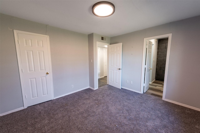 unfurnished bedroom with visible vents, baseboards, connected bathroom, and dark carpet