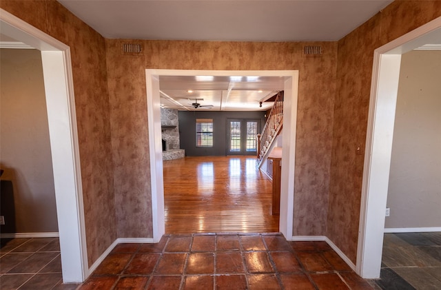 corridor featuring stairway, baseboards, and visible vents