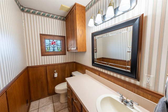 bathroom featuring a wainscoted wall, visible vents, toilet, wallpapered walls, and tile patterned flooring