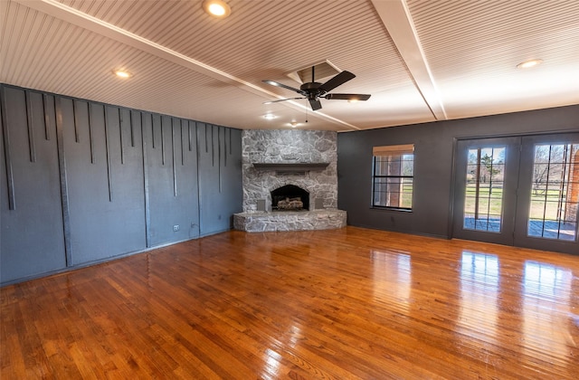 unfurnished living room featuring beam ceiling, hardwood / wood-style flooring, a fireplace, and ceiling fan