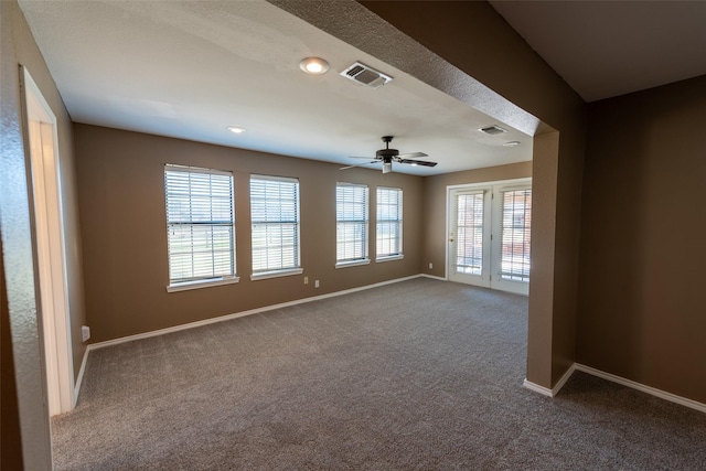 carpeted spare room featuring visible vents, a ceiling fan, and baseboards