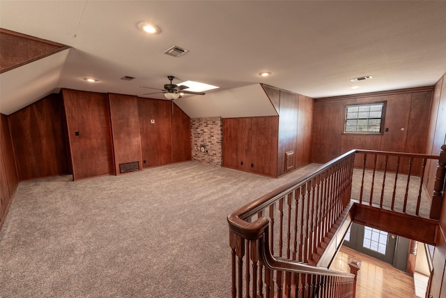 bonus room featuring visible vents, carpet floors, wooden walls, and vaulted ceiling