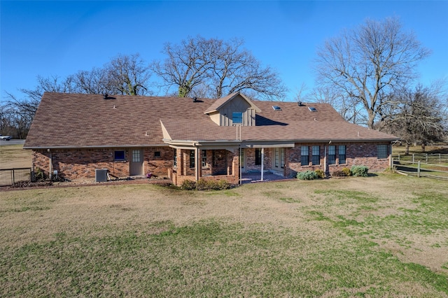 back of property featuring brick siding, a lawn, and fence