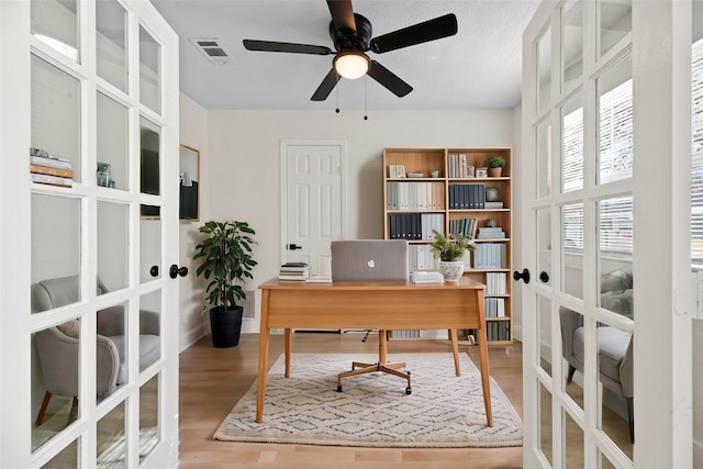 home office with ceiling fan, light hardwood / wood-style floors, and french doors