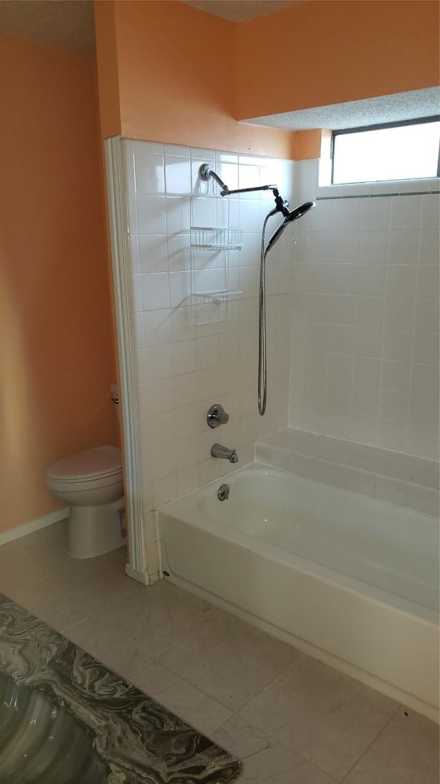 bathroom featuring tile patterned flooring, tiled shower / bath, and toilet