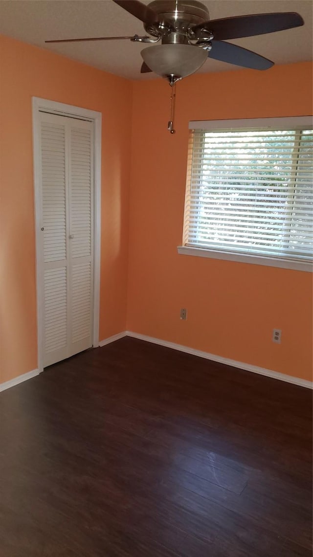 unfurnished bedroom featuring dark wood-type flooring, a closet, and ceiling fan