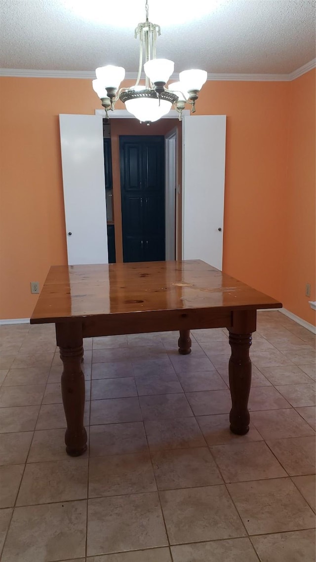 unfurnished dining area featuring ornamental molding, a chandelier, tile patterned flooring, and a textured ceiling