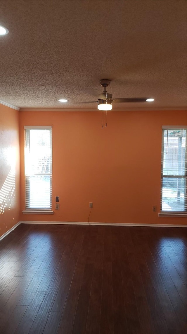 empty room with ornamental molding, dark wood-type flooring, ceiling fan, and a textured ceiling