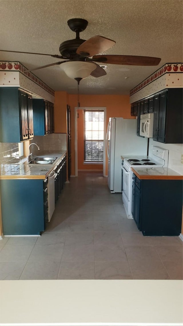 kitchen featuring blue cabinetry, sink, light tile patterned flooring, and white appliances