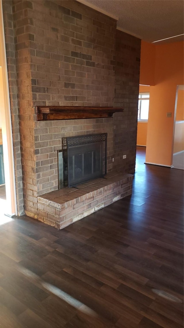 unfurnished living room with a brick fireplace and dark hardwood / wood-style floors