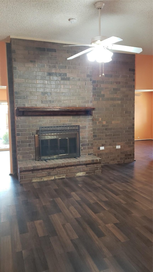 unfurnished living room with ceiling fan, a fireplace, dark hardwood / wood-style flooring, and a textured ceiling