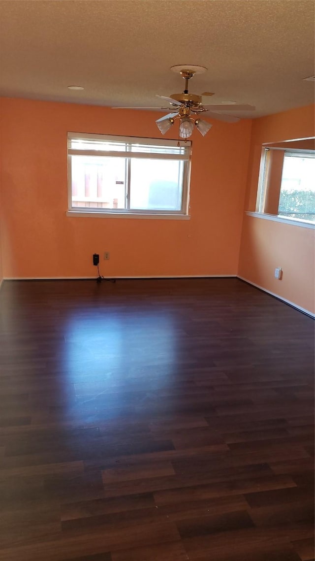 unfurnished room with ceiling fan, dark hardwood / wood-style flooring, and a textured ceiling