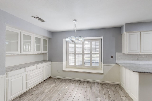 unfurnished dining area featuring light hardwood / wood-style floors and an inviting chandelier