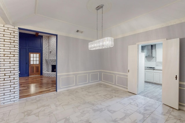 unfurnished dining area featuring a fireplace and an inviting chandelier