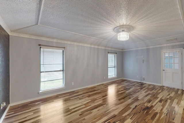 empty room with ornamental molding, a notable chandelier, and hardwood / wood-style flooring