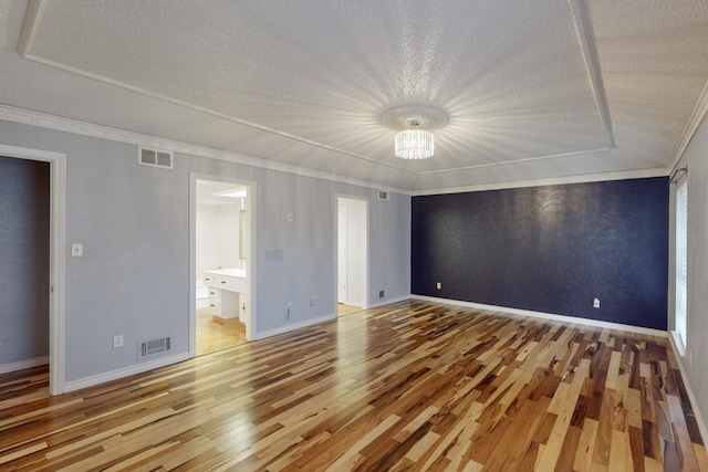 unfurnished bedroom with ensuite bath, an inviting chandelier, crown molding, a textured ceiling, and hardwood / wood-style flooring