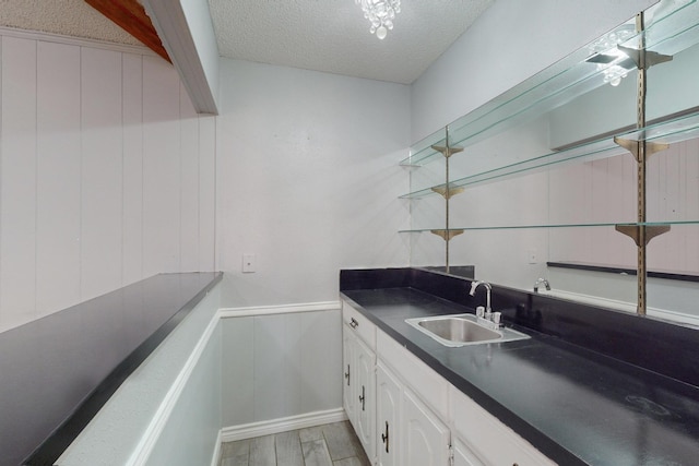 kitchen featuring a textured ceiling, white cabinetry, and sink