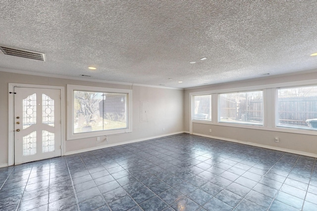 empty room with a textured ceiling, crown molding, dark tile patterned floors, and a healthy amount of sunlight