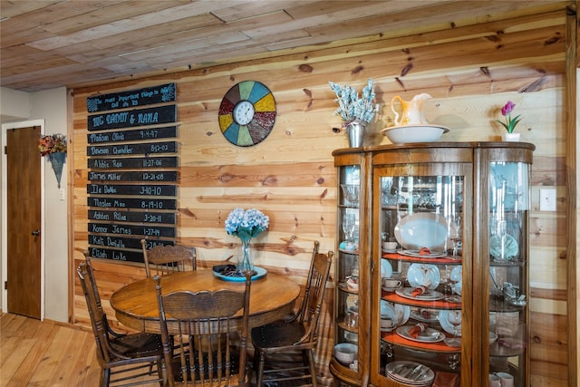 dining area with hardwood / wood-style flooring, wooden walls, and wood ceiling