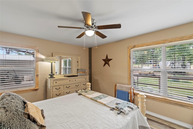 bedroom featuring ceiling fan, hardwood / wood-style floors, and multiple windows