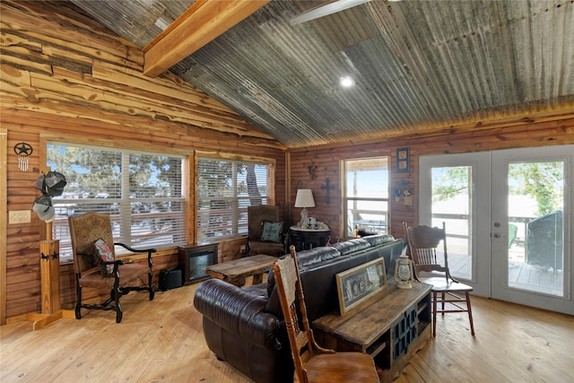 living room with wood walls, lofted ceiling with beams, light hardwood / wood-style floors, and french doors