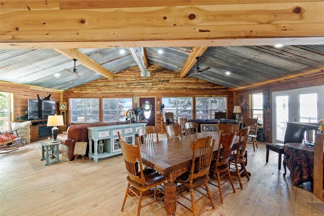 dining space featuring vaulted ceiling with beams, light hardwood / wood-style floors, plenty of natural light, and wooden walls