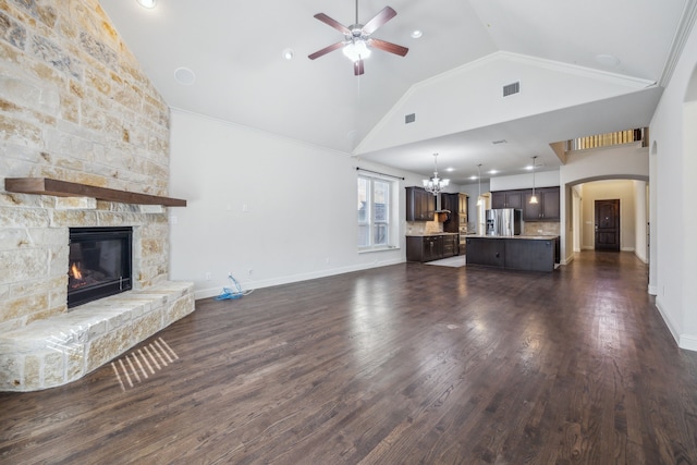 unfurnished living room with dark hardwood / wood-style flooring, high vaulted ceiling, ceiling fan with notable chandelier, and a fireplace