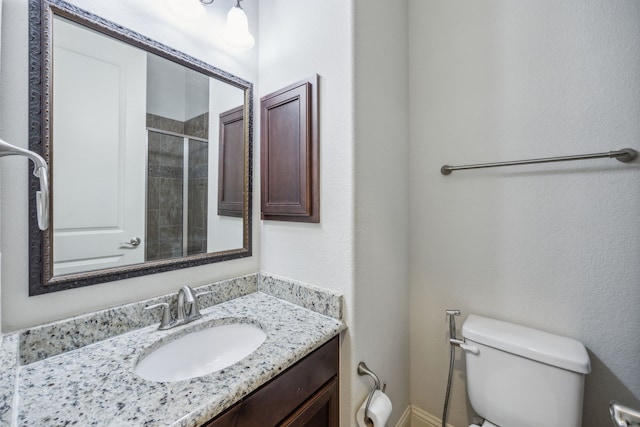 bathroom featuring toilet, vanity, and walk in shower