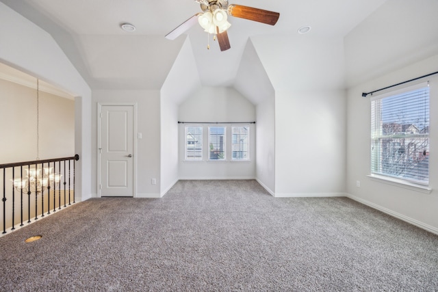 interior space with vaulted ceiling, carpet, and ceiling fan with notable chandelier