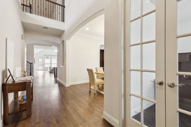 hallway featuring french doors, crown molding, dark wood-type flooring, and a high ceiling