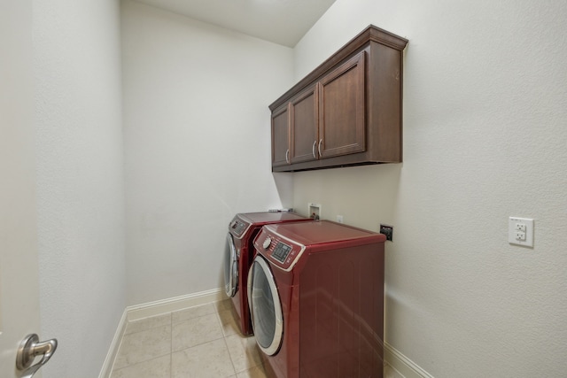 laundry room with cabinets, light tile patterned floors, and washer and clothes dryer