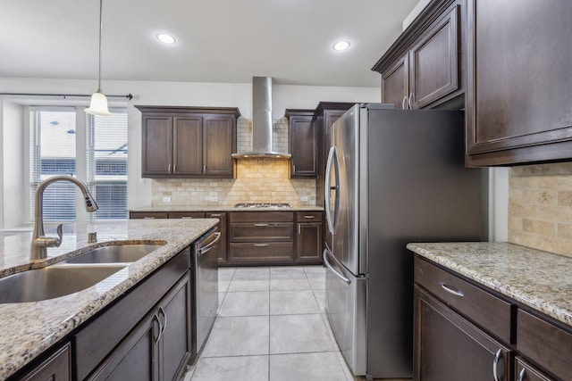 kitchen featuring sink, pendant lighting, light stone counters, and wall chimney exhaust hood