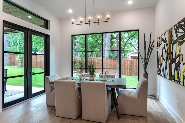 dining room featuring baseboards, a notable chandelier, a healthy amount of sunlight, and light wood finished floors