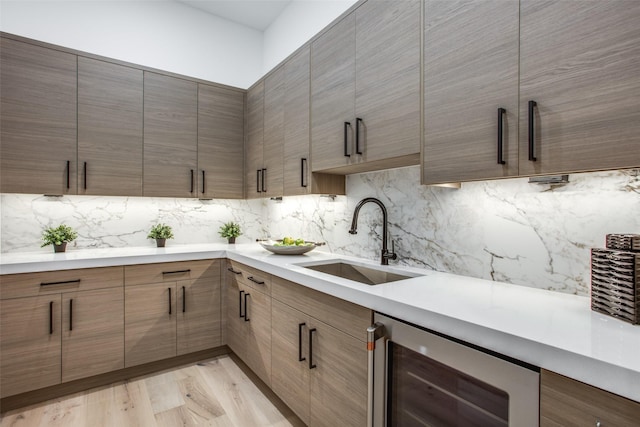 kitchen featuring light countertops, wine cooler, modern cabinets, and a sink