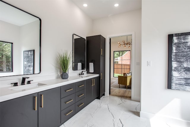 bathroom featuring a sink, marble finish floor, recessed lighting, and double vanity